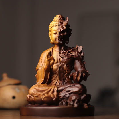 A carved Buddha statue with a split design, showing a golden Buddha figure on one half and a dark brown skull-faced counterpart on the other, seated on a wooden base.