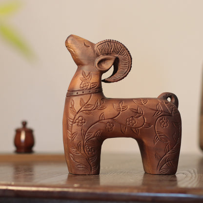 A carved wooden ram figurine with floral engravings, displayed on a wooden surface against a soft beige background.