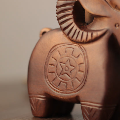 Close-up of a carved wooden ram figurine with a star emblem on its side, showing warm brown wood grain and textured details.